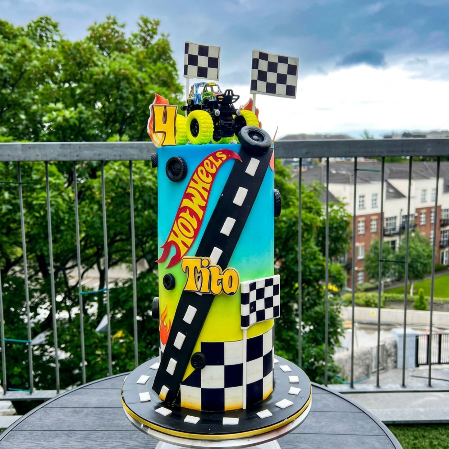 Rainbow gradient racing cake with black racetrack and monster truck topper for a 40th birthday, CakeMeAway Dublin