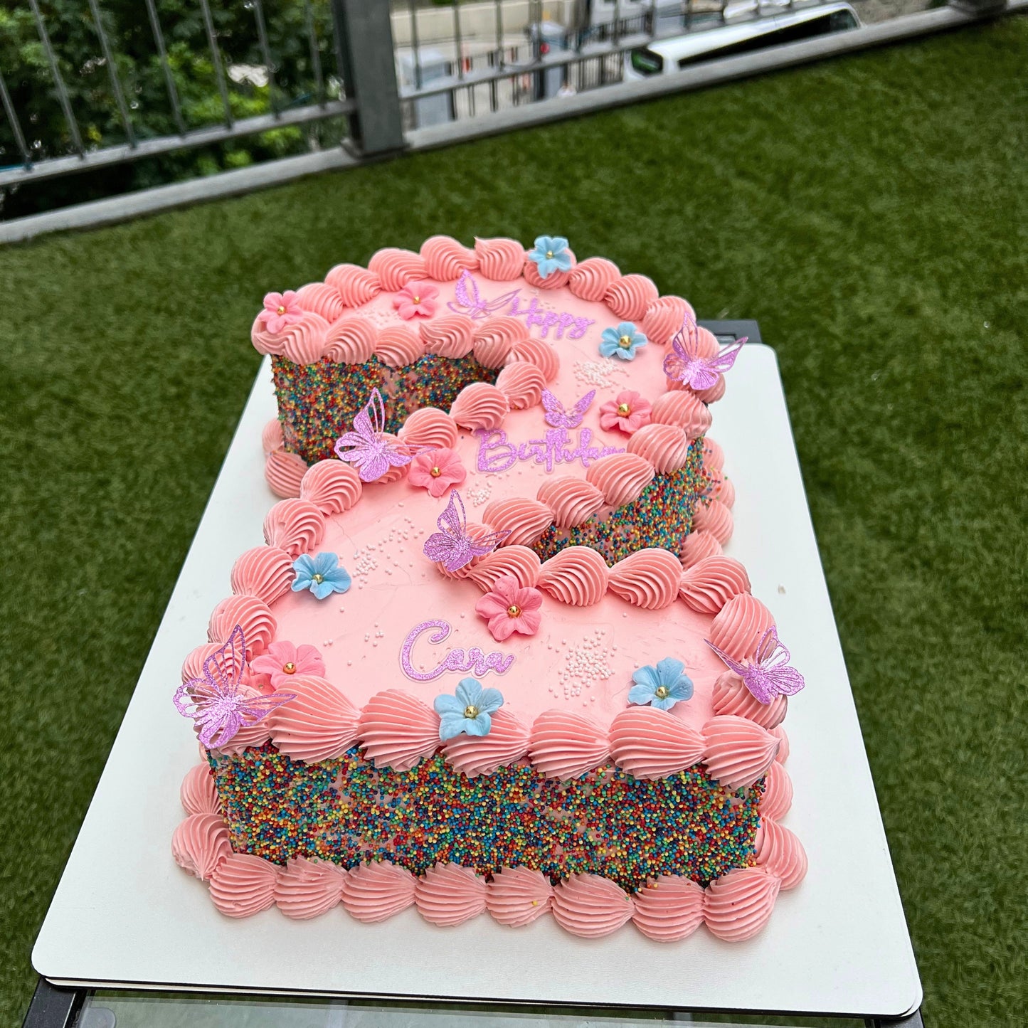 Pink buttercream number cake with piped shells, sprinkle sides, sugar flowers and butterflies, Dublin