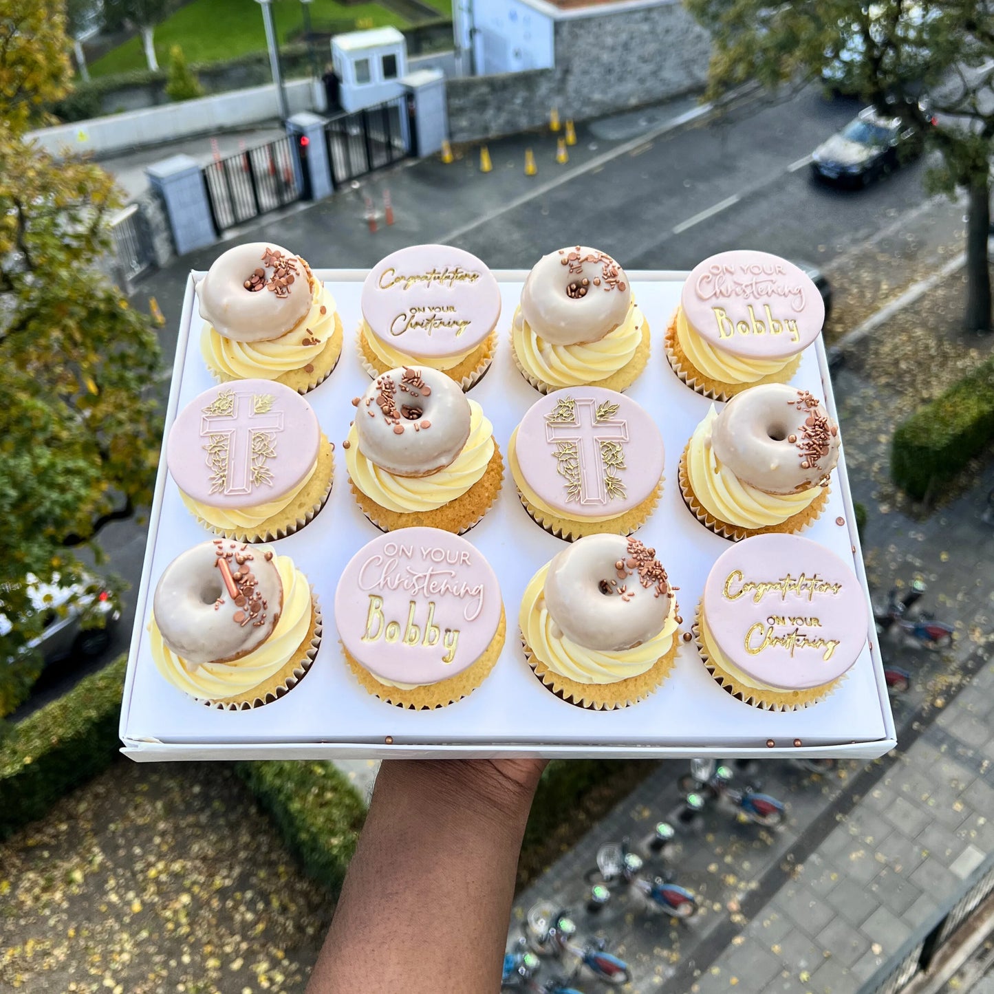 Box of communion cupcakes with personalized messages held outdoors