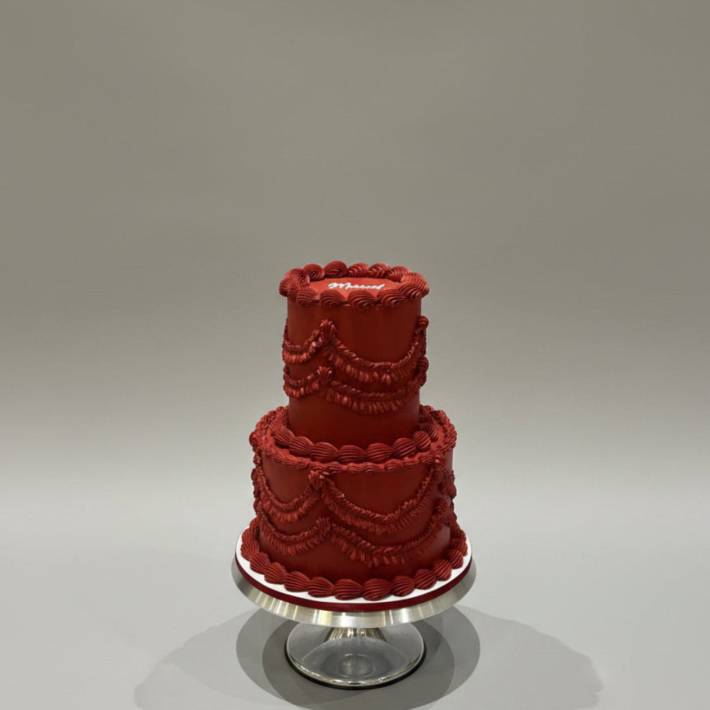 A heart-shaped frosted cake with 'Happy Married Life' written on top, displayed on a white square cake box against a white marble background.