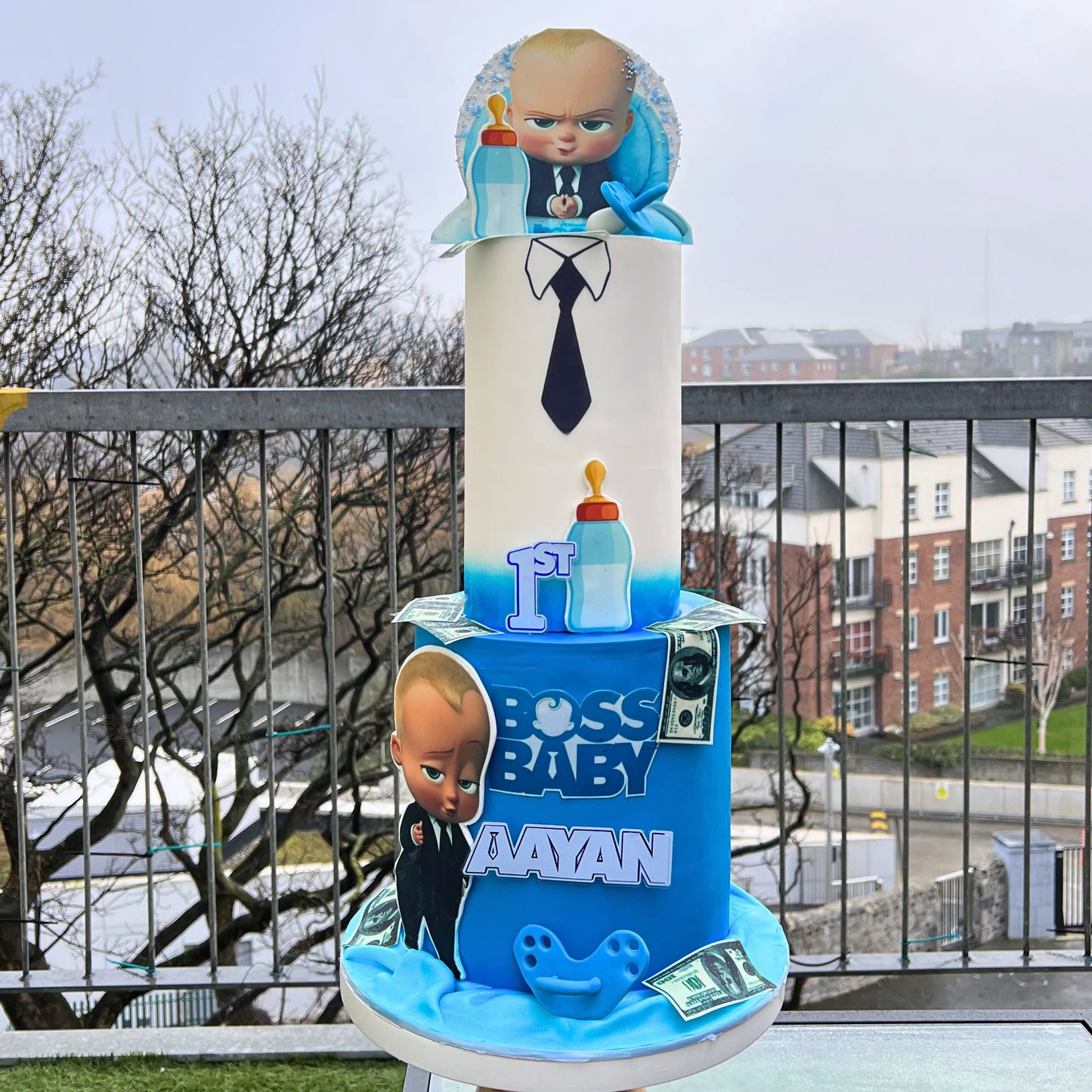 Decorative item with 'Baby boss cake ' branding on a stand outdoors.