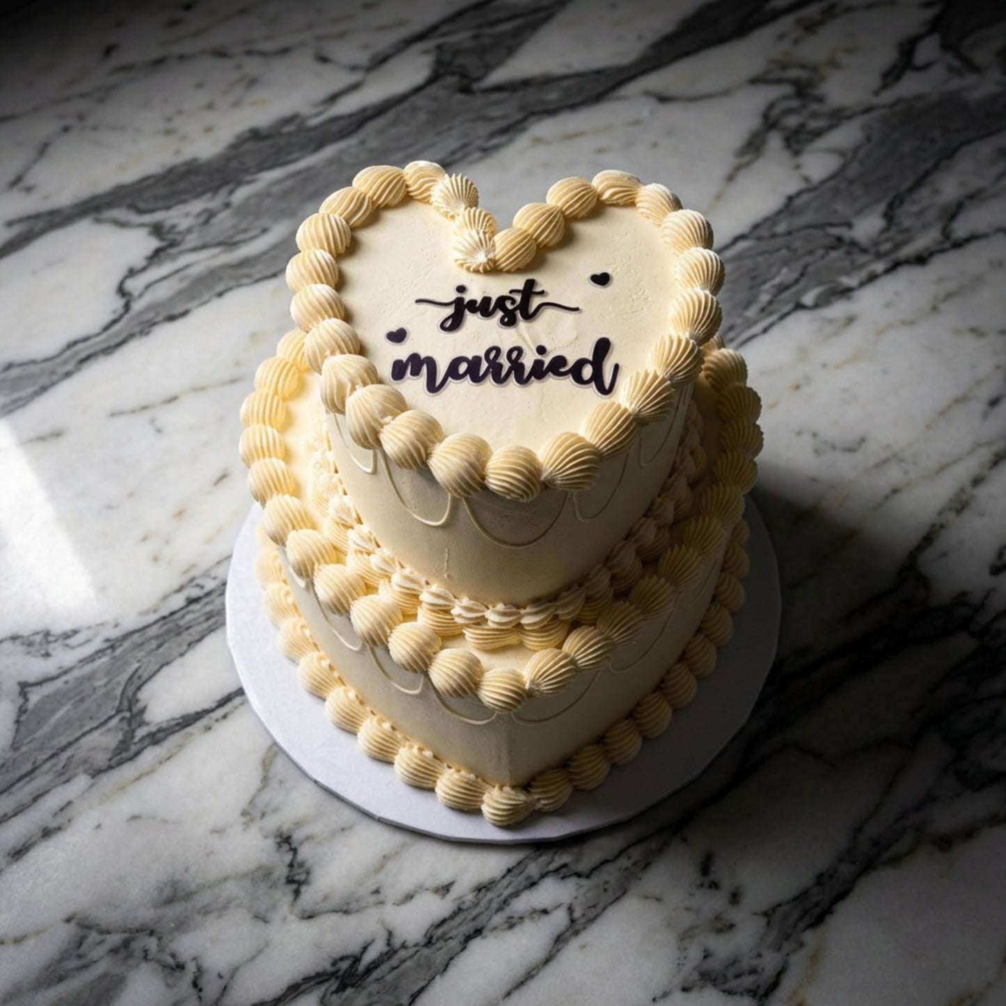Two tier ivory heart shaped Lambeth wedding cake with hand-piped buttercream shells and just married plaque, handmade in Dublin by CakeMeAway