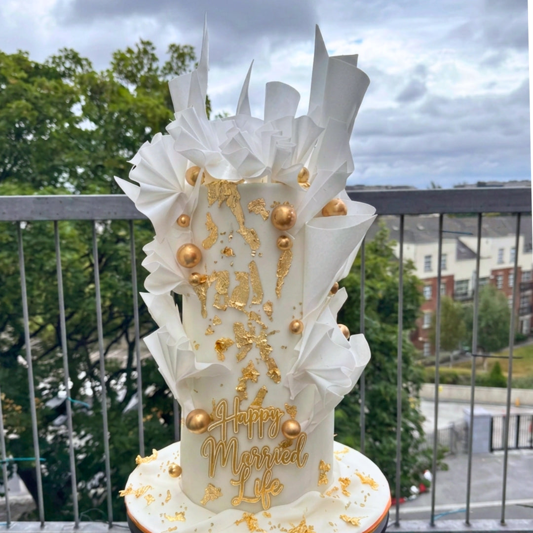Tall white wedding cake with ruffled wafer paper, gold leaf detailing and hand-rolled gold spheres, CakeMeAway Dublin