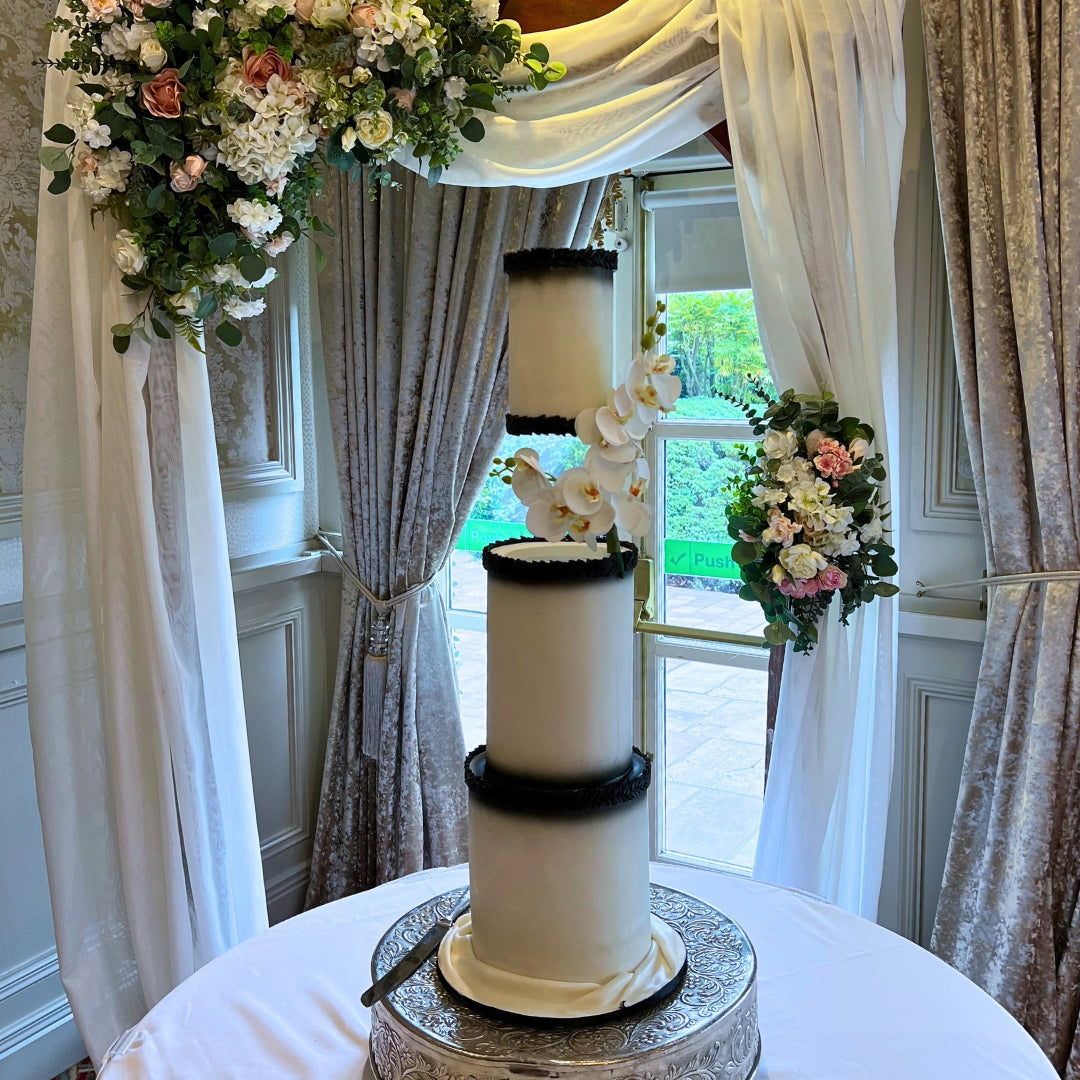 Ivory and black floating wedding cake with white orchids at a Dublin wedding venue