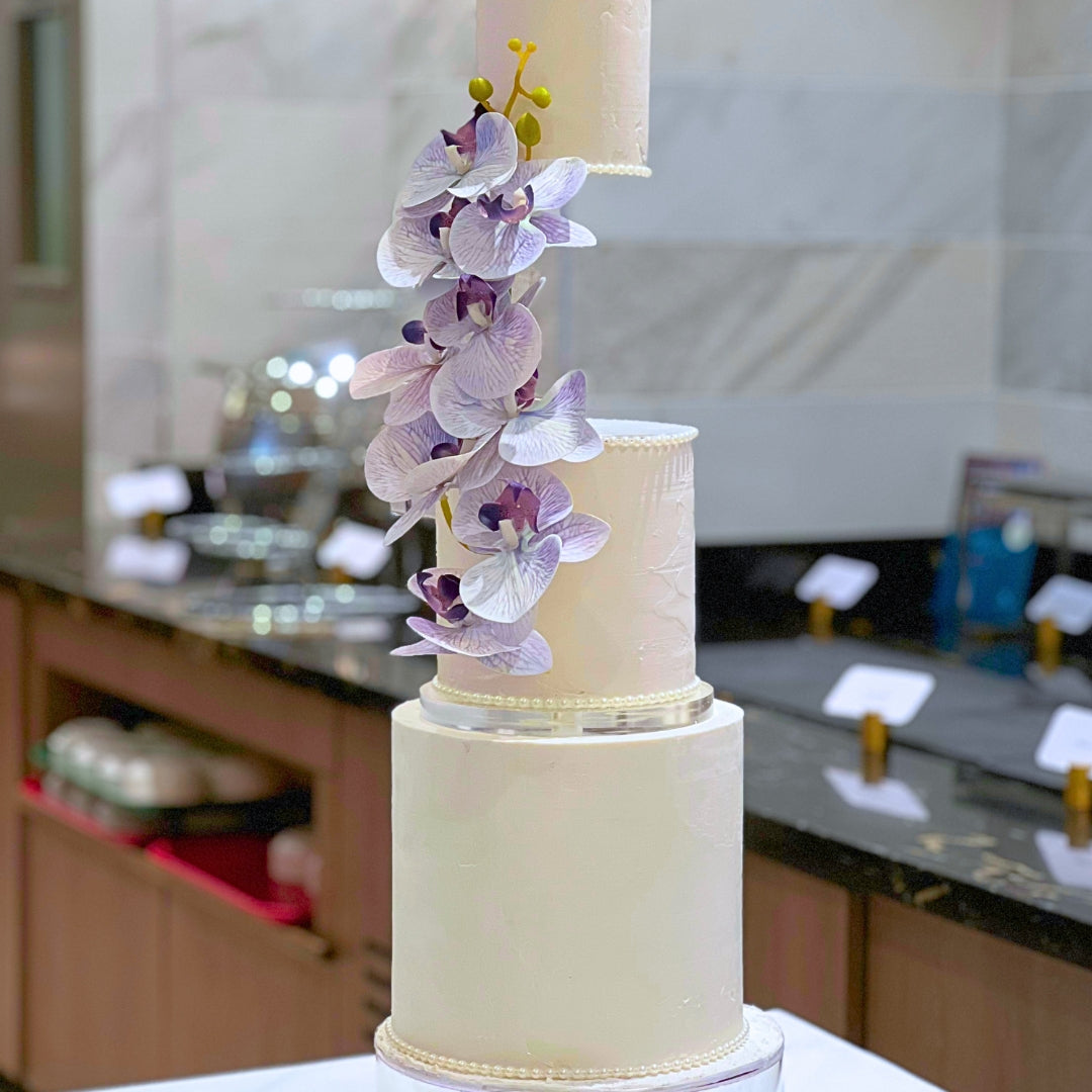 Three tier suspended wedding cake in blush and ivory with textured buttercream and lilac orchid cascade, handmade in Dublin by CakeMeAway