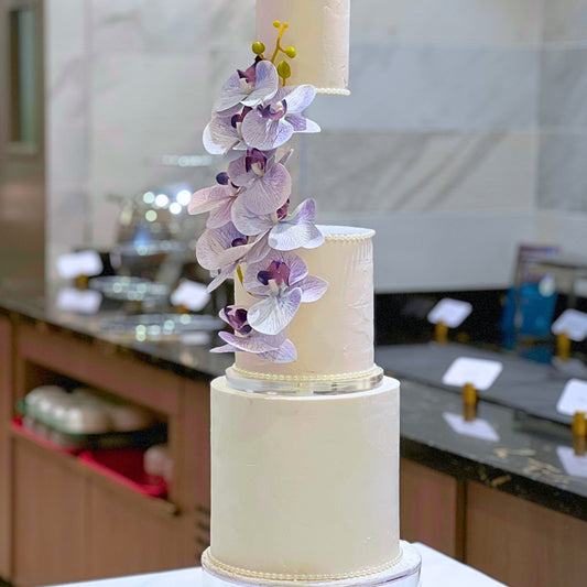 Three tier suspended wedding cake in blush and ivory with textured buttercream and lilac orchid cascade, handmade in Dublin by CakeMeAway