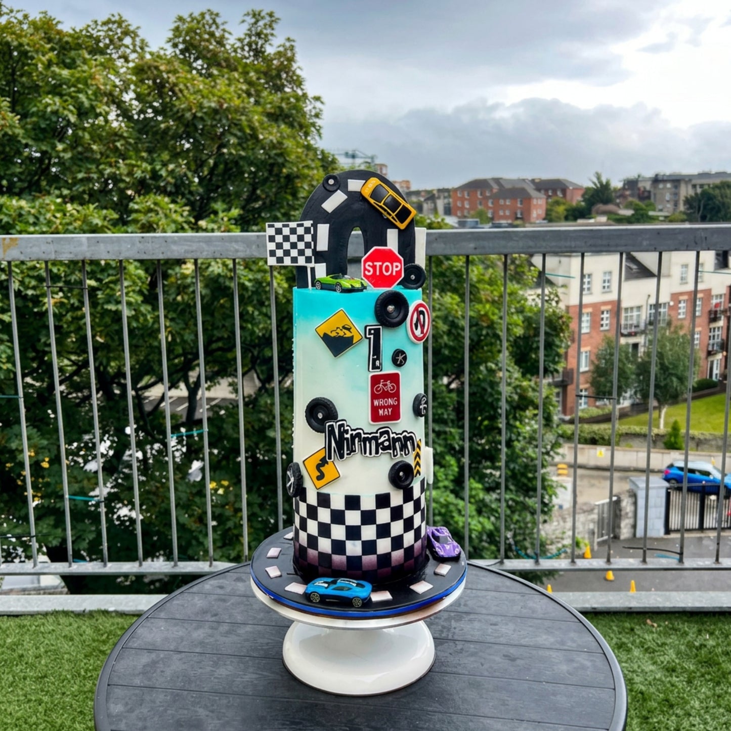Race car themed birthday cake with checkerboard band, road signs and loop track topper, Dublin