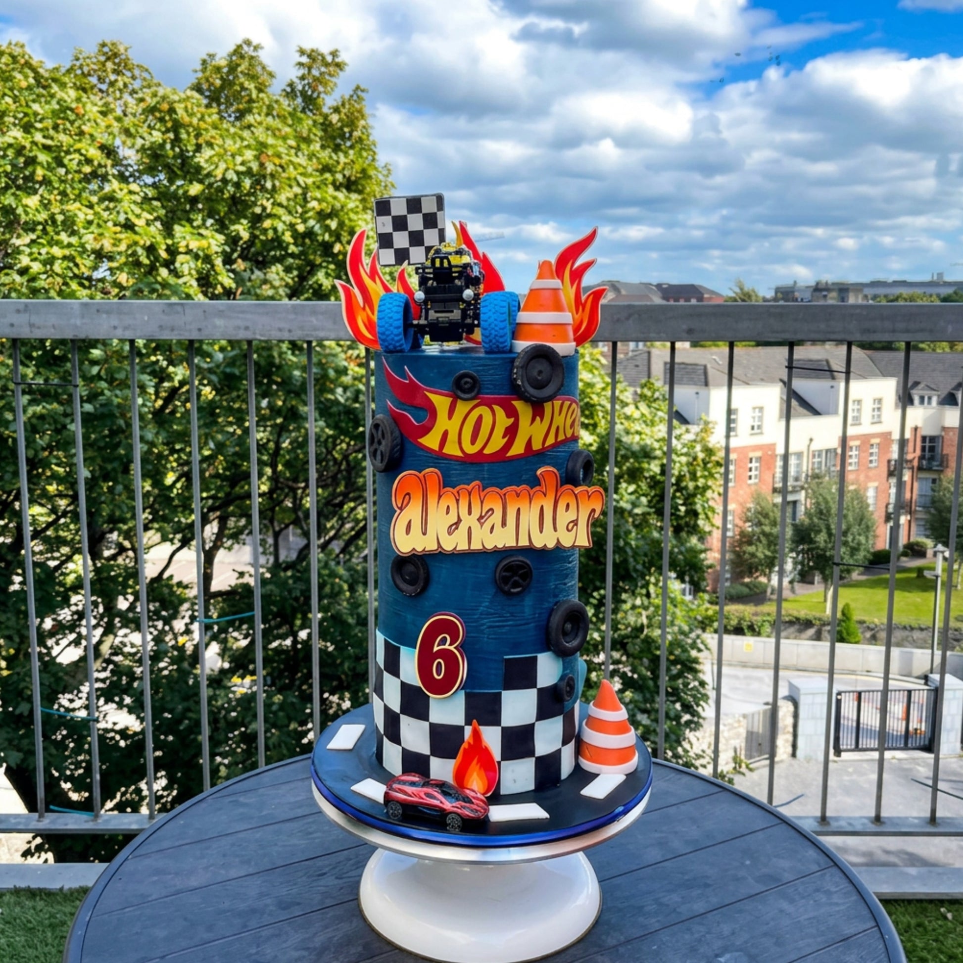 Navy racing birthday cake with checkered flag, traffic cones and monster truck topper, CakeMeAway Dublin