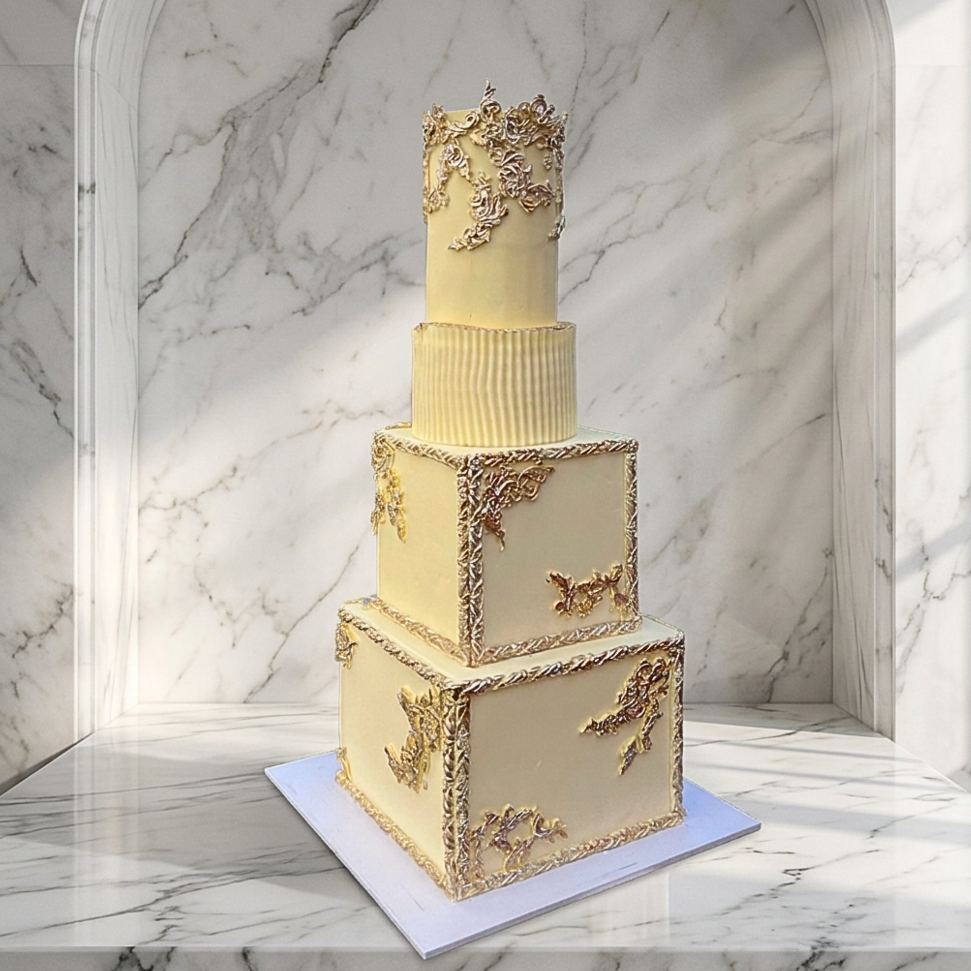 Ivory and gold four tier wedding cake with gilded scrollwork and hand-sculpted pleated tier, Dublin