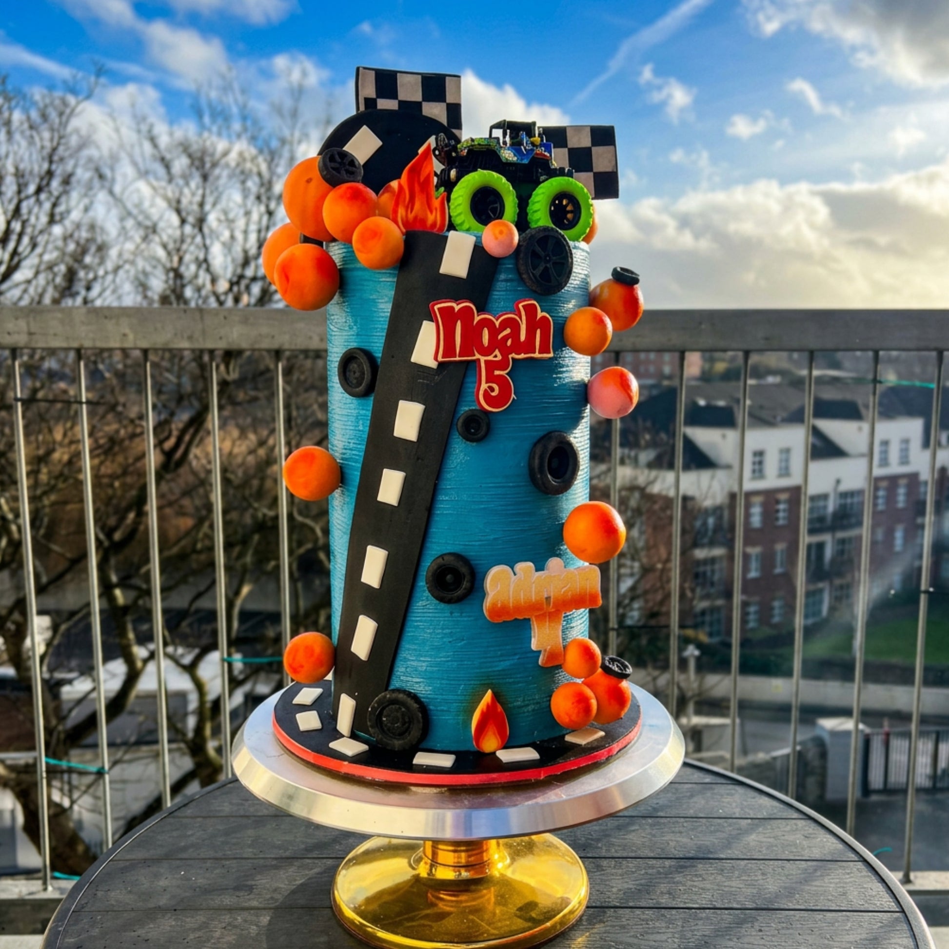 Turquoise race car cake with orange sphere garland, racetrack and two personalised names, Dublin