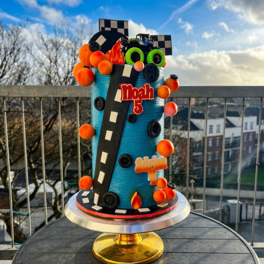 Turquoise race car cake with orange sphere garland, racetrack and two personalised names, Dublin