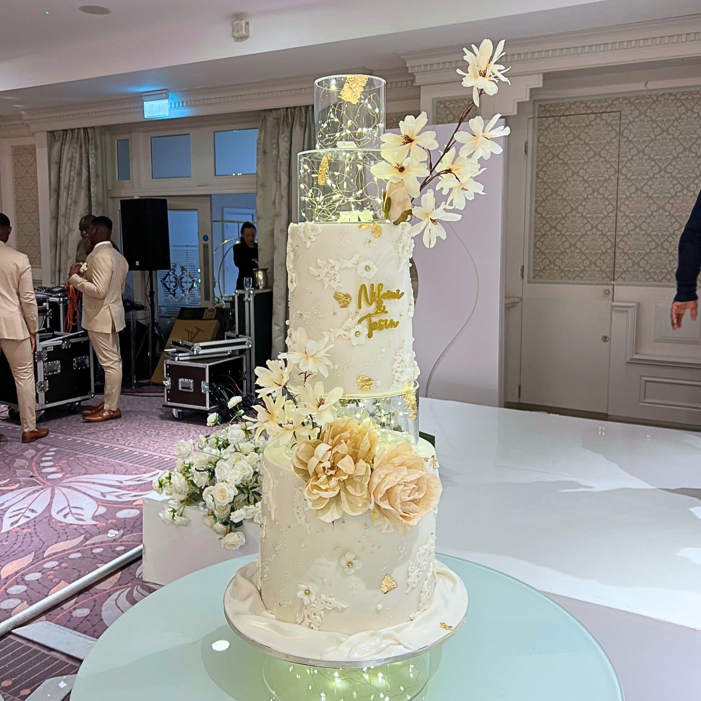 Four tier illuminated wedding cake with lit clear tiers, lace detailing and sugar peonies at a Dublin wedding venue, CakeMeAway