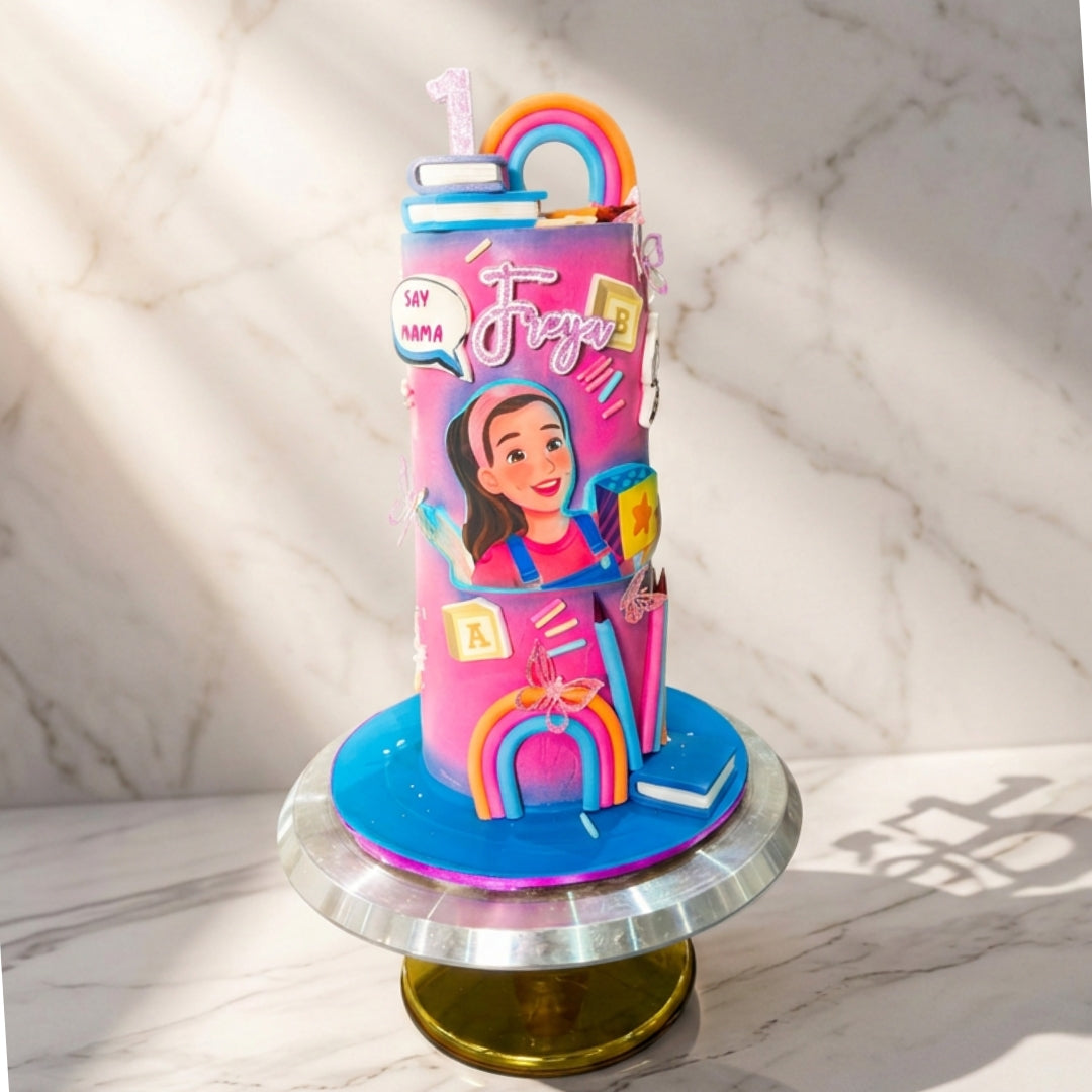 Pink and blue ombre 1st birthday cake with fondant rainbows, alphabet blocks, books and personalised name topper, handmade in Dublin by CakeMeAway