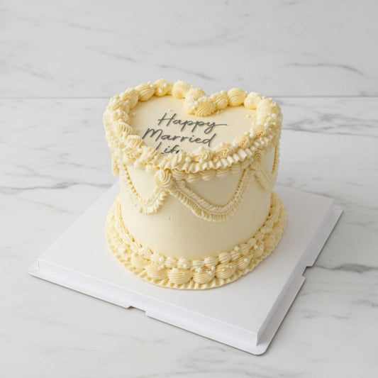 A round frosted cake with piped cream icing and the words '3. commercial photography packshot, white marble counter top seamless backdrop, neutral lighting
 Married Life' on top, held on a white board outdoors with a city street and buildings in the background.