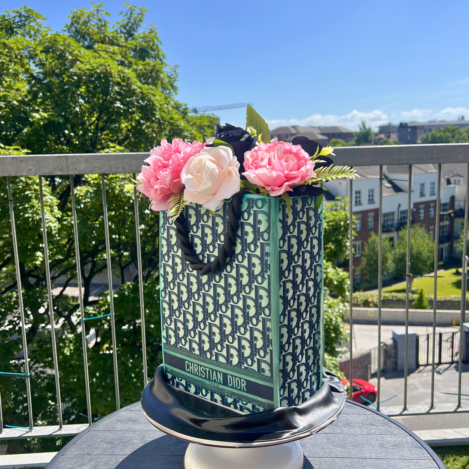 Christian Dior shopping bag cake with flowers on a balcony