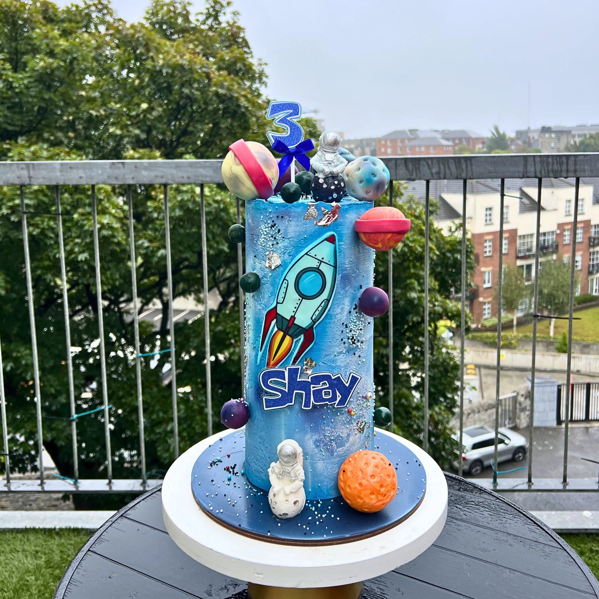 Children's birthday cake with space-themed decorations on a balcony