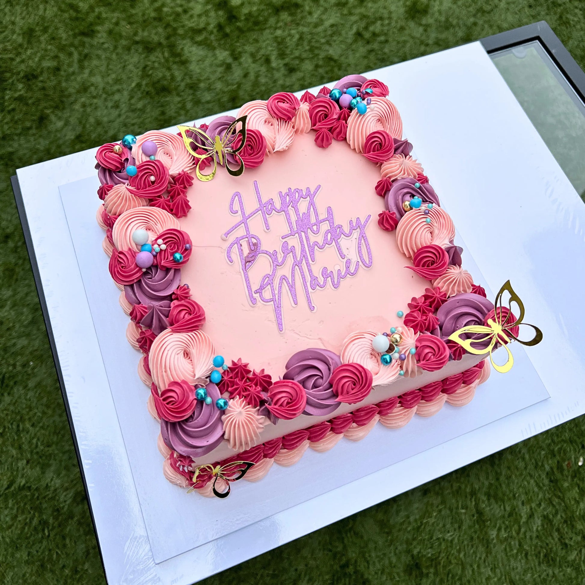Decorative birthday cake with pink and purple frosting on a white plate.