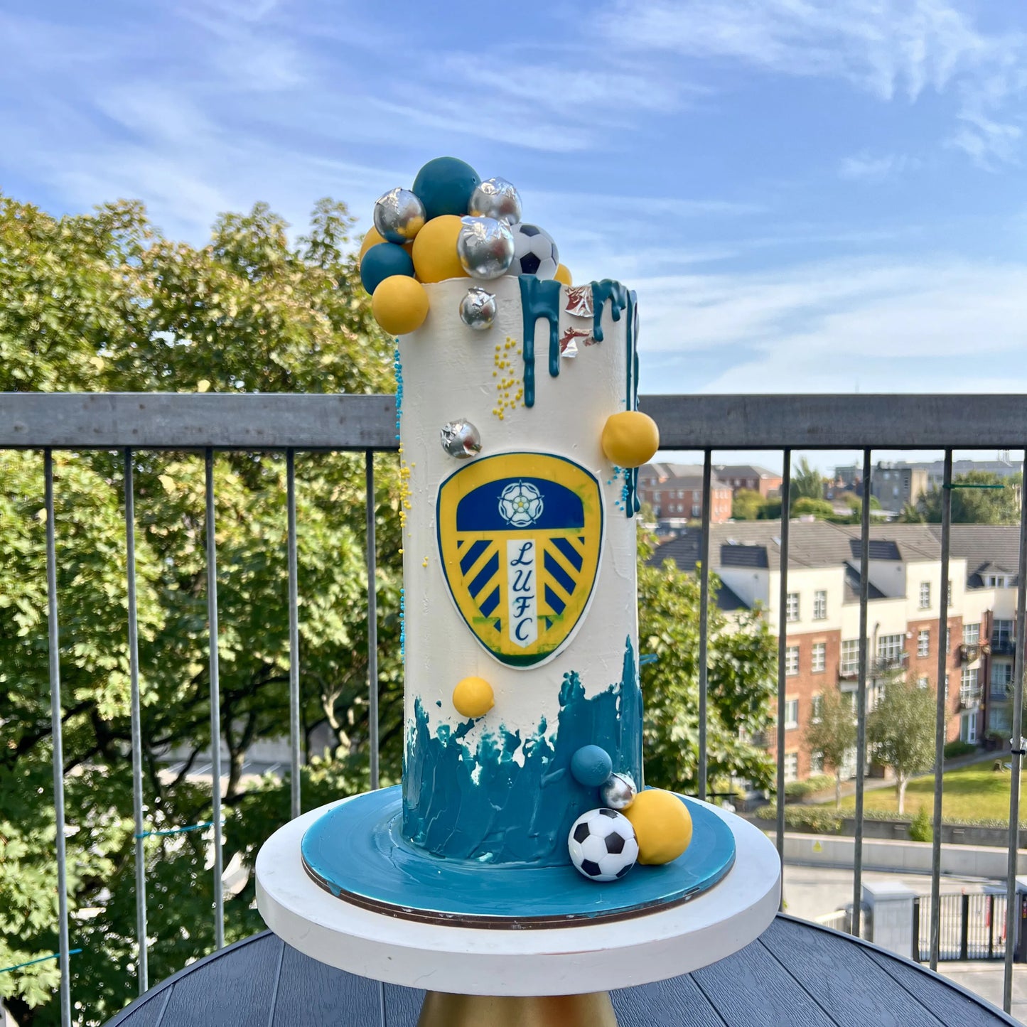 Decorative cake with sports theme on a balcony with a cityscape background