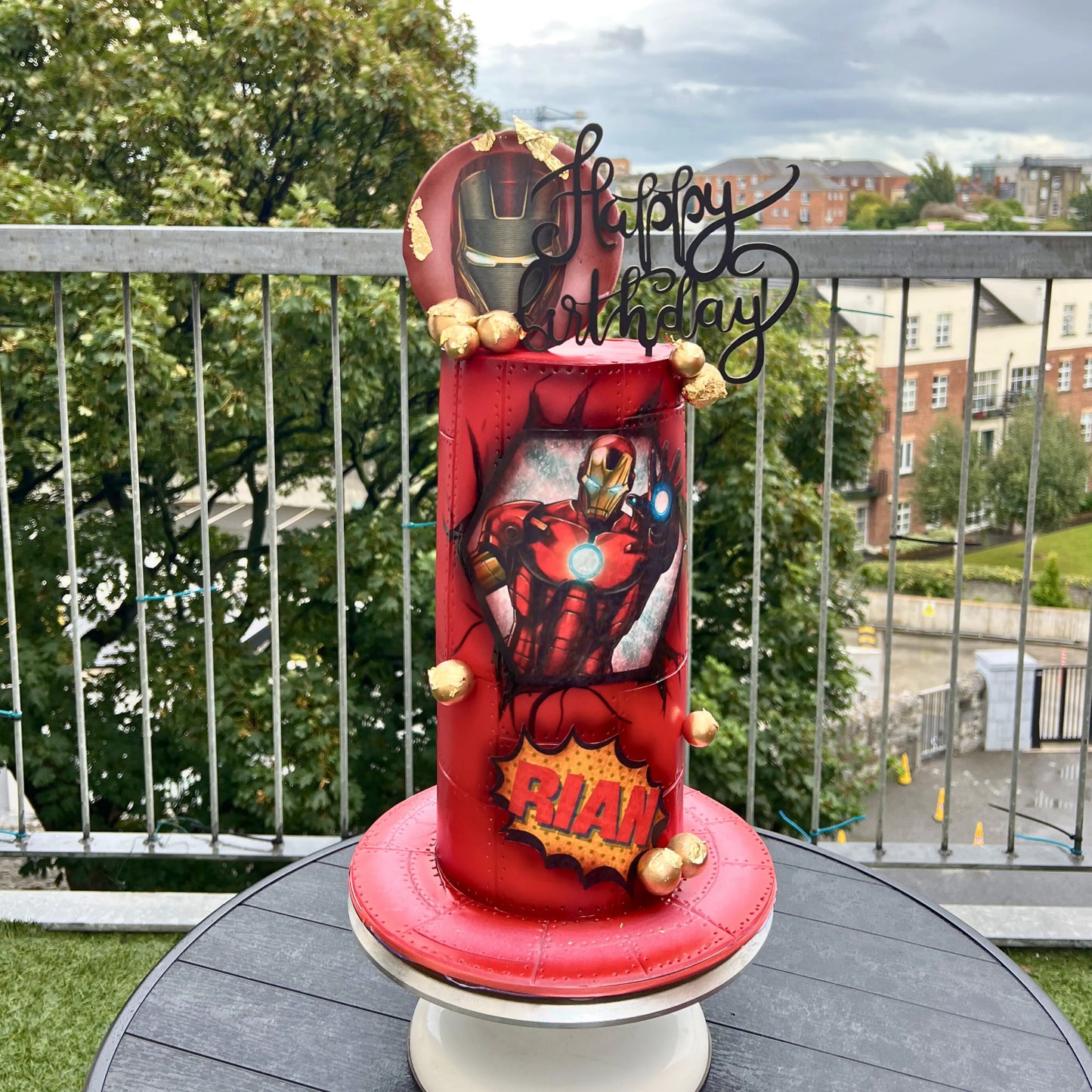 Red Iron man birthday cake with superhero design on a table outdoors