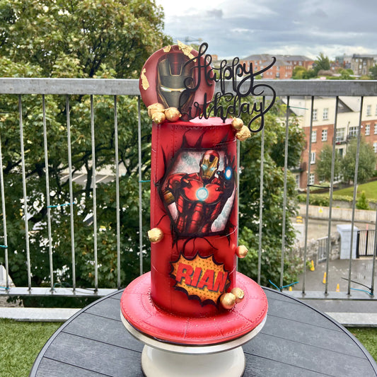Red Iron man birthday cake with superhero design on a table outdoors