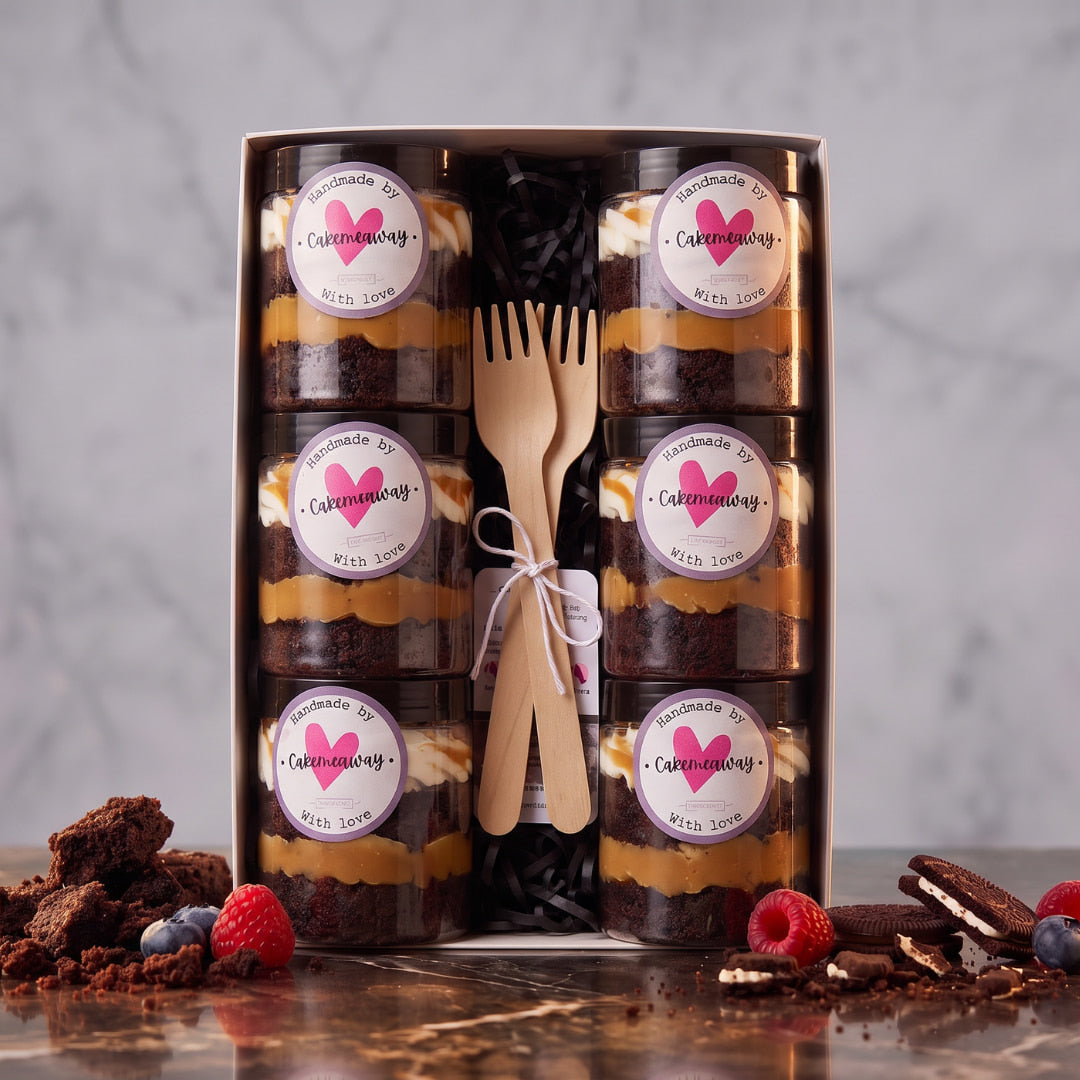 Six chocolate and caramel cake jars with cream topping in a white gift box, styled with berries and chocolate cookies, Dublin