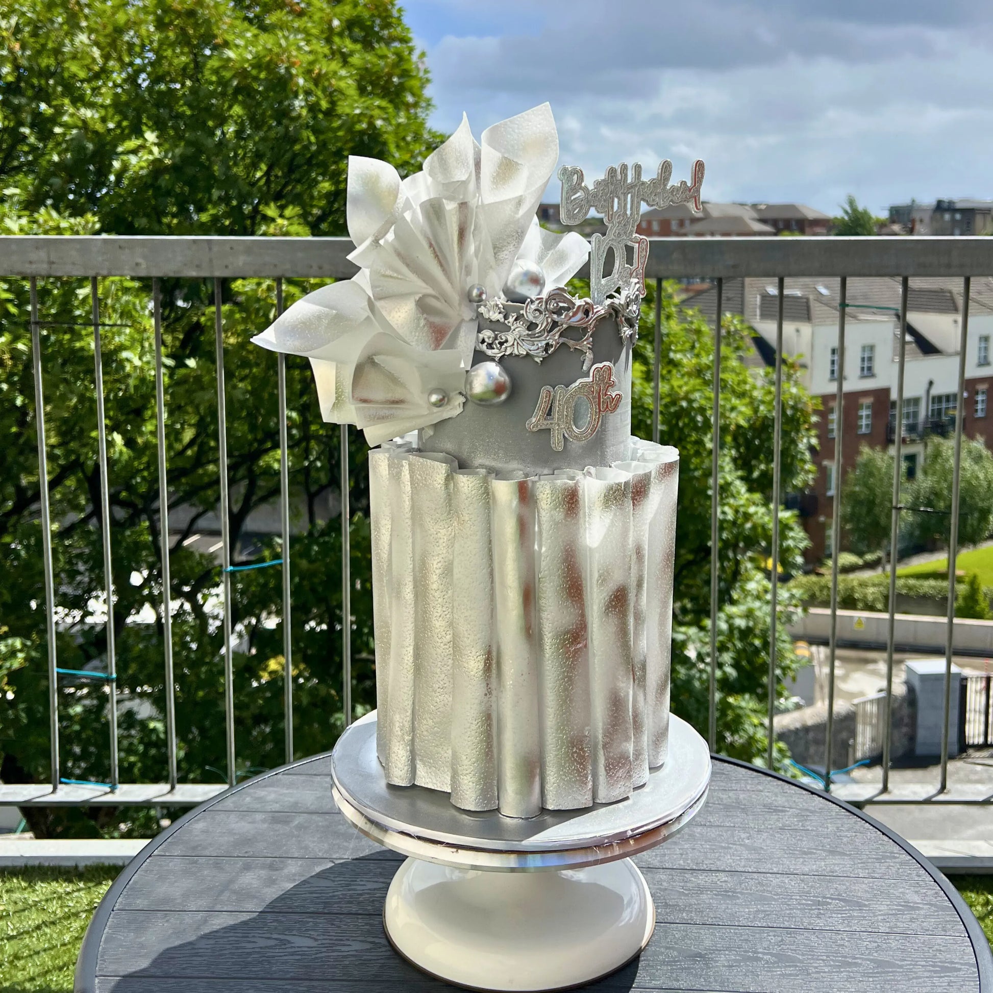 Silver Wafer Wrapped birthday cake with decorative elements on a table outdoors