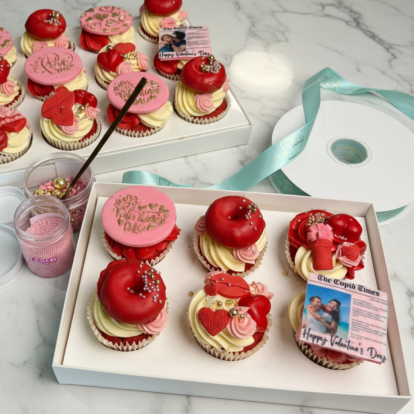 Valentine's Day-themed cupcakes in white boxes with decorative elements.