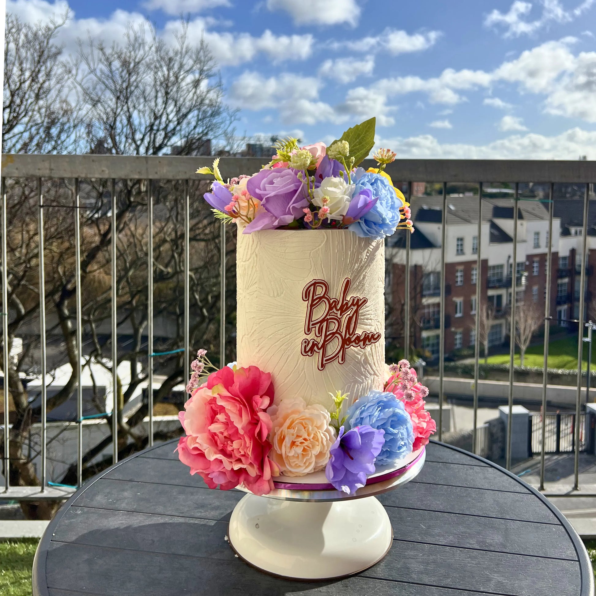baby in bloom baby shower cake with flowers on a table outdoors