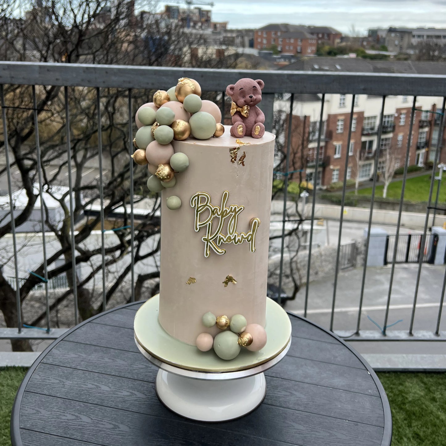 Baby shower cake with decorative elements on a table outdoors.