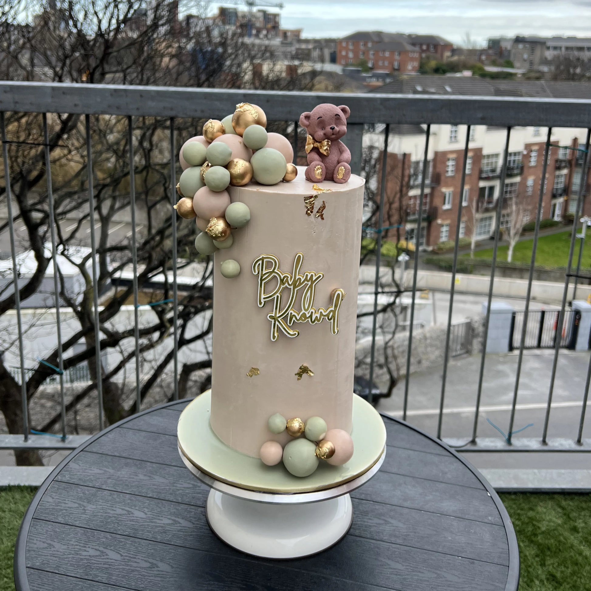 Baby shower cake with decorative elements on a table outdoors.