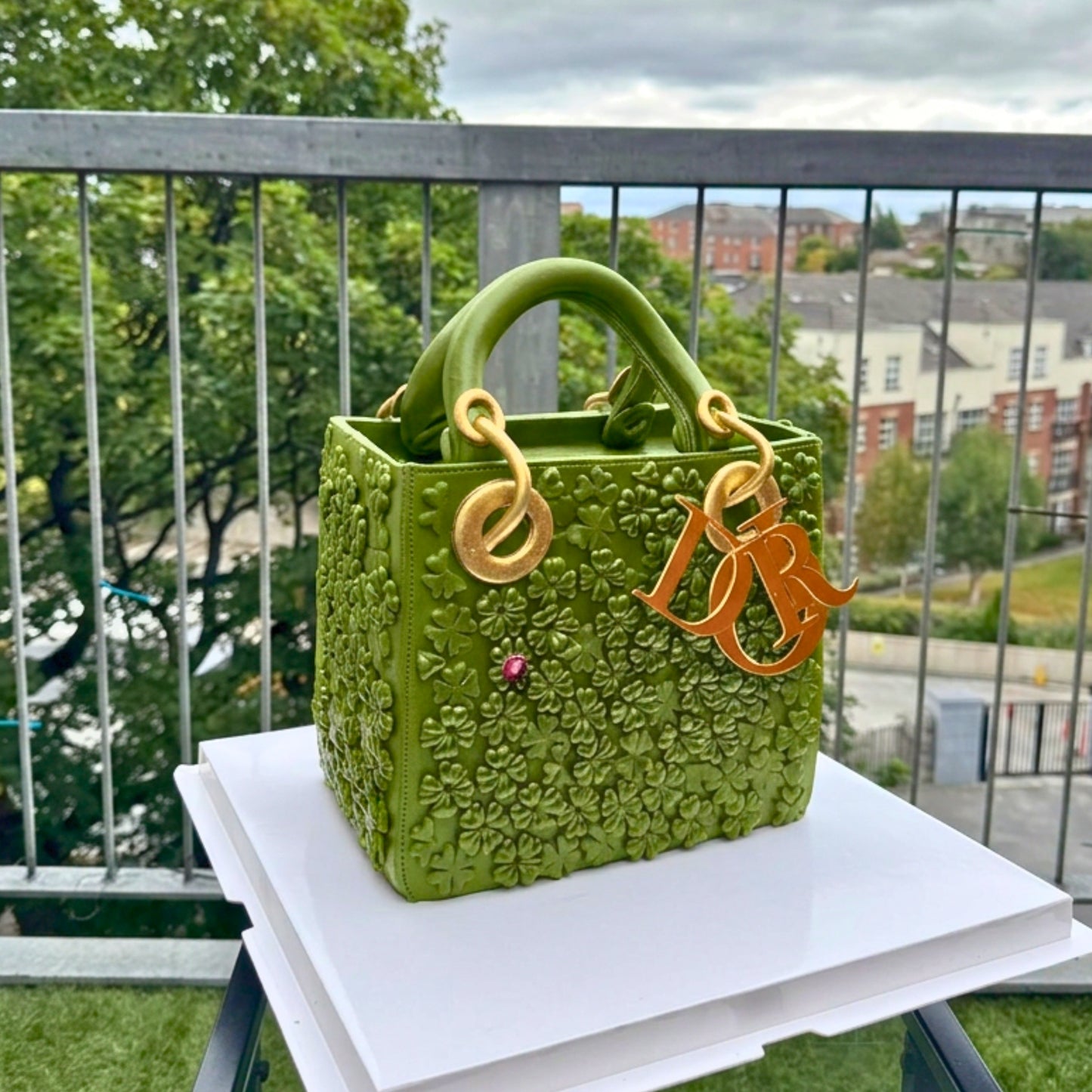 Black quilted handbag cake with hand-painted clover and ladybird charms, made in Dublin