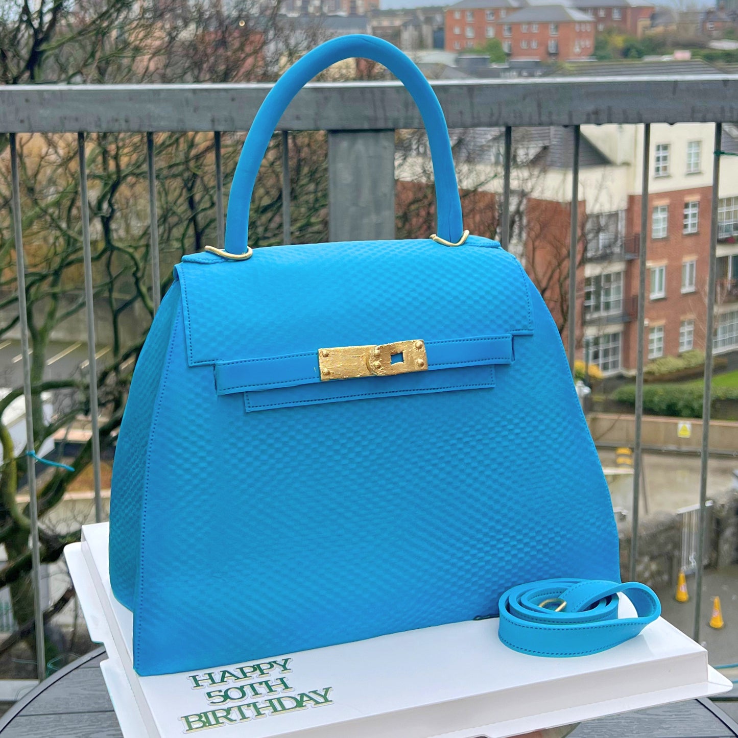 Dsigner Blue structured handbag cake with a gold turn-lock and single top handle