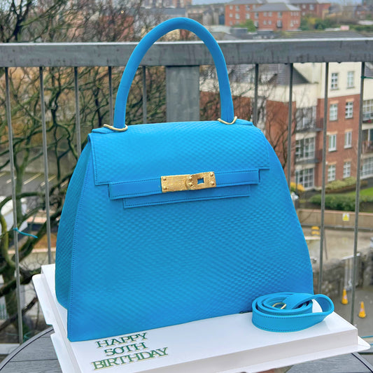 Blue structured handbag cake with a gold turn-lock and single top handle, made in Dublin