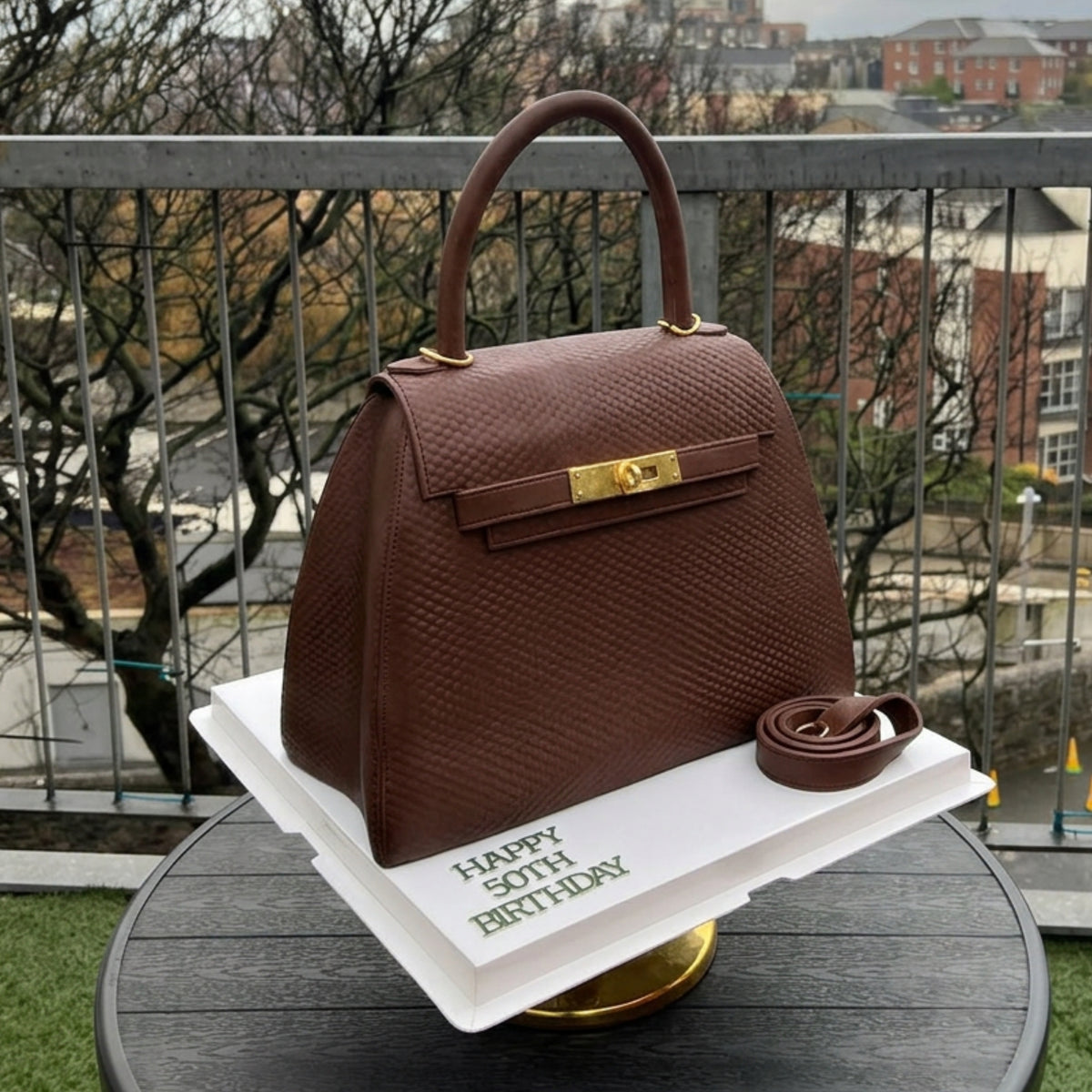 Brown structured handbag cake with a gold turn-lock and single top handle