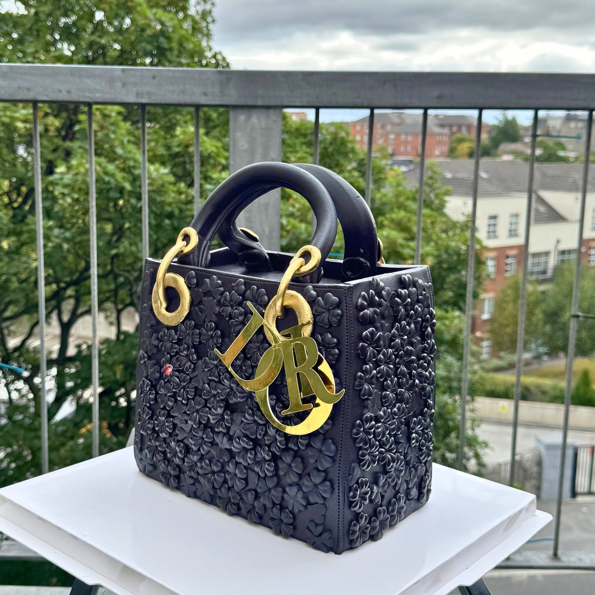 Hand-painted sugar clover and red ladybird charms on a black quilted bag cake