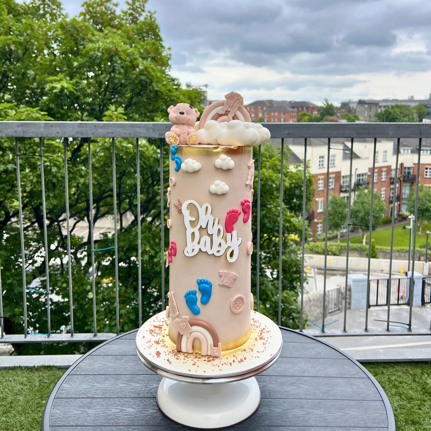 Decorative cake with 'Oh Baby' text on a stand outdoors