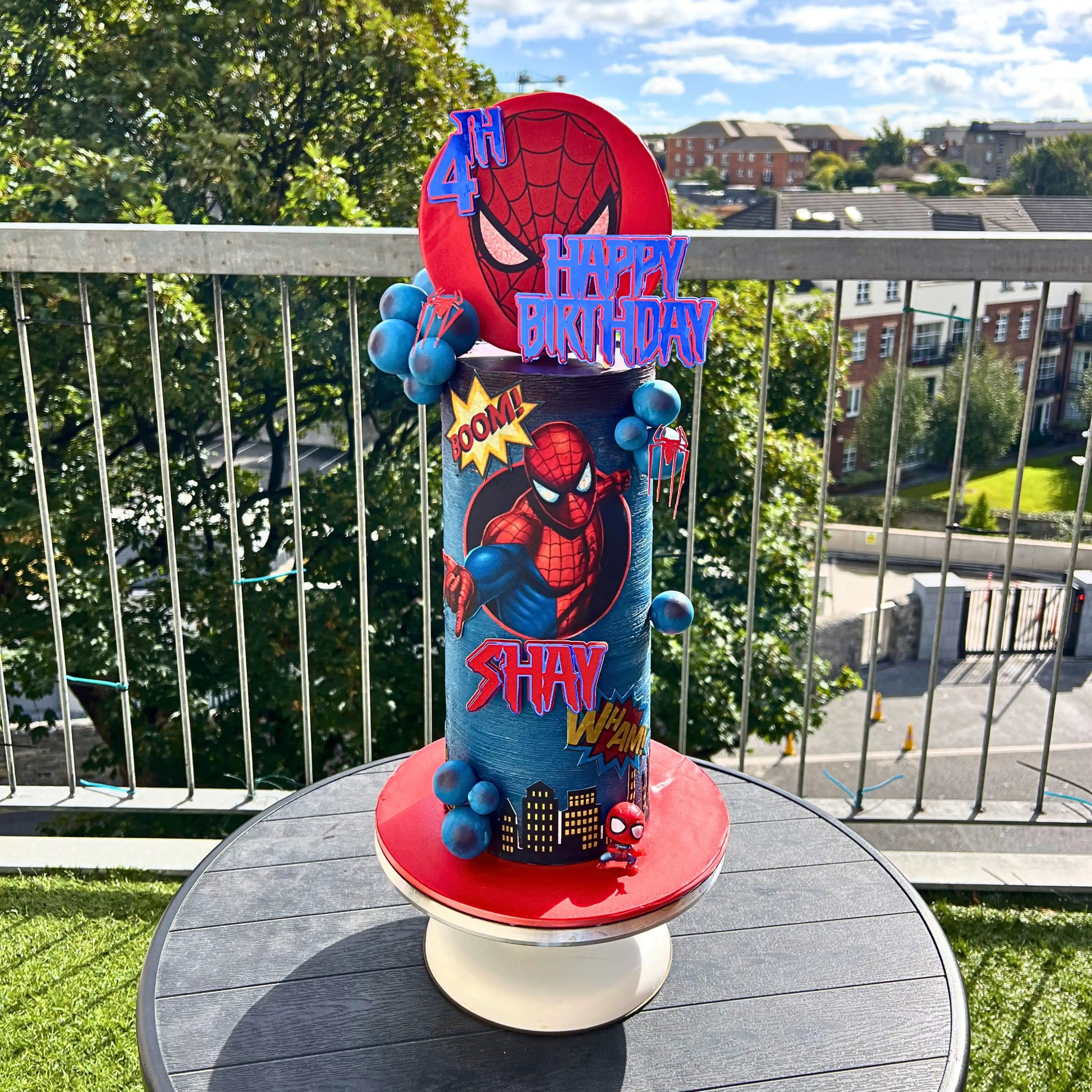 Spider-Man themed birthday cake on a table with a cityscape background