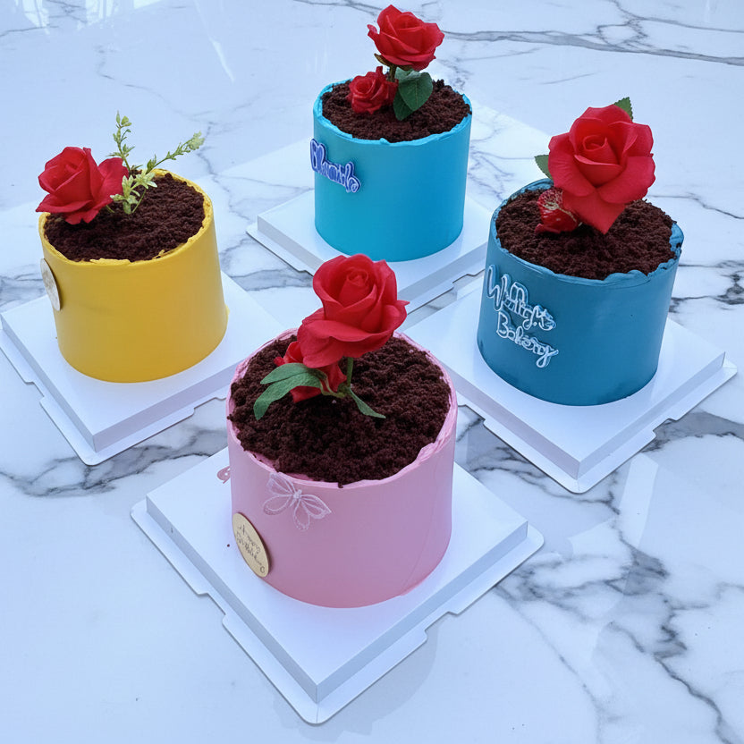 Four small cakes with red roses on a white surface outdoors.