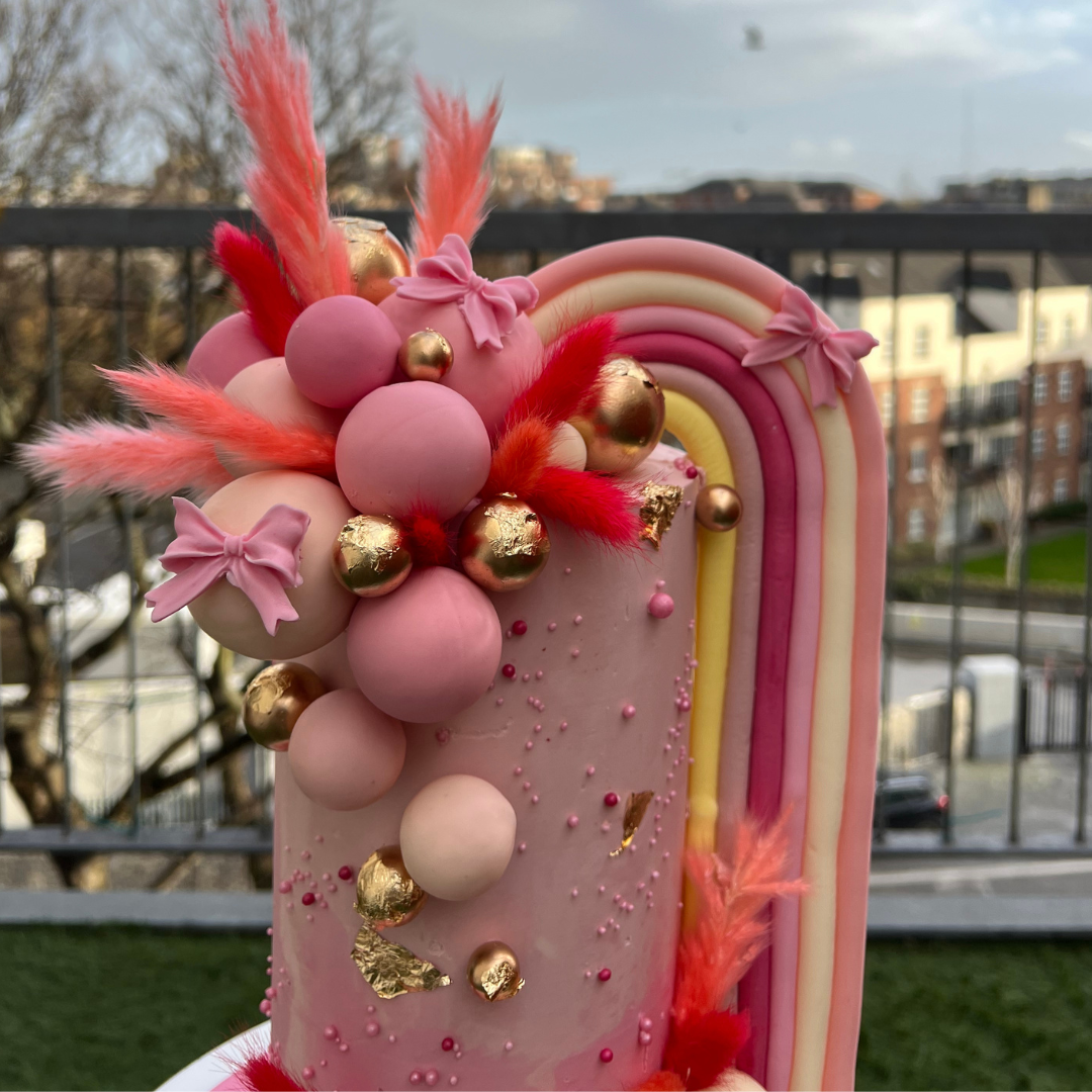 elaborate pastel pink cake witha a giant rainbow