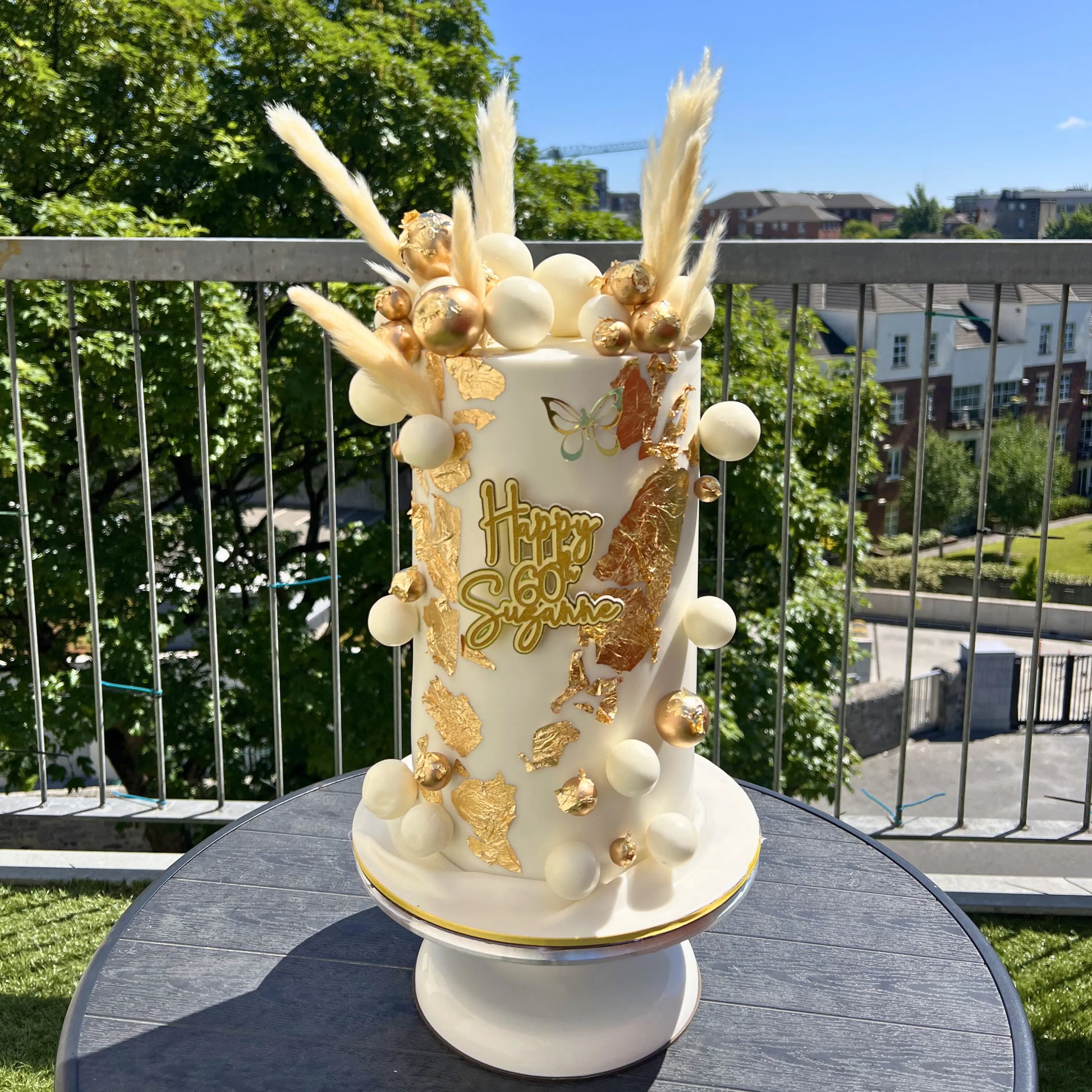 Decorative cake with gold and white elements on a table outdoors
