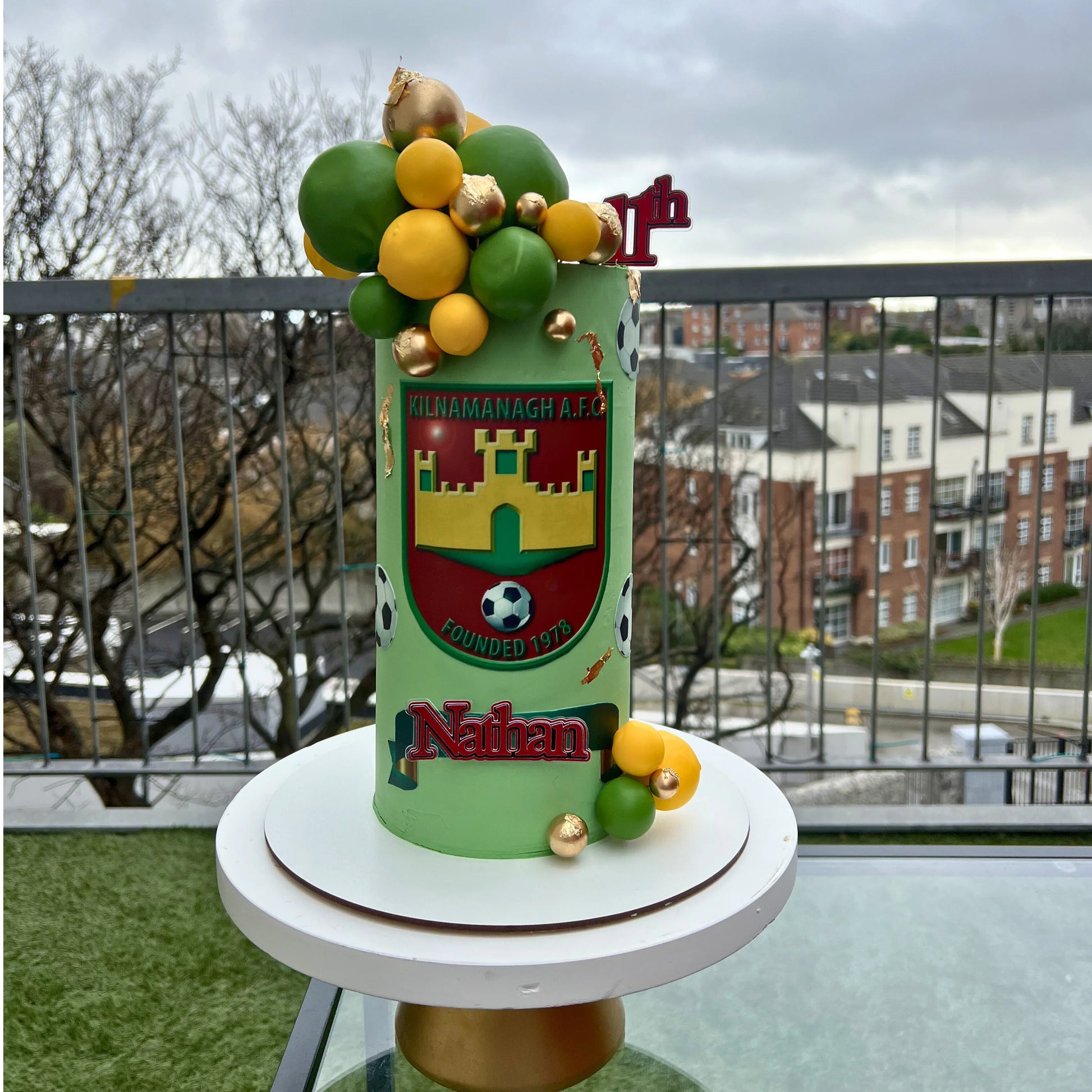 Decorative cake with balloons on a rooftop with a cityscape background