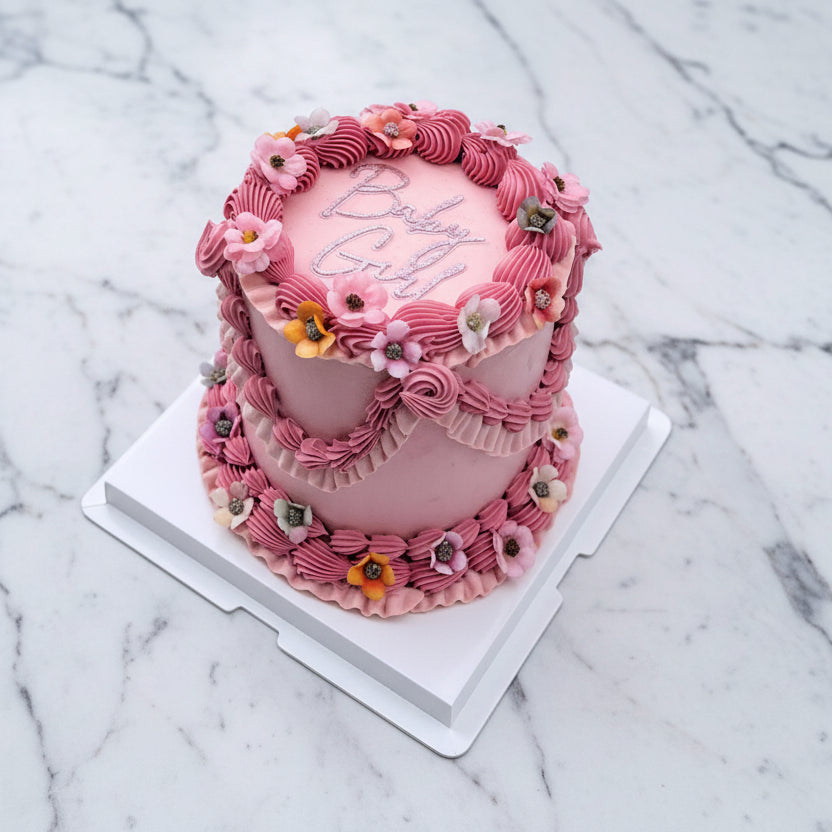 Pink cake with floral decorations on a white tiled floor