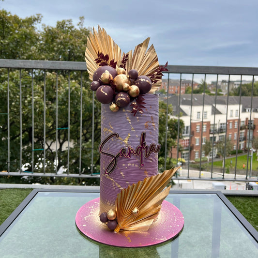 Tall luxury purple buttercream cake with hand-painted gold leaf accents and artistic floral textures, bespoke design by CakeMeAway Dublin.