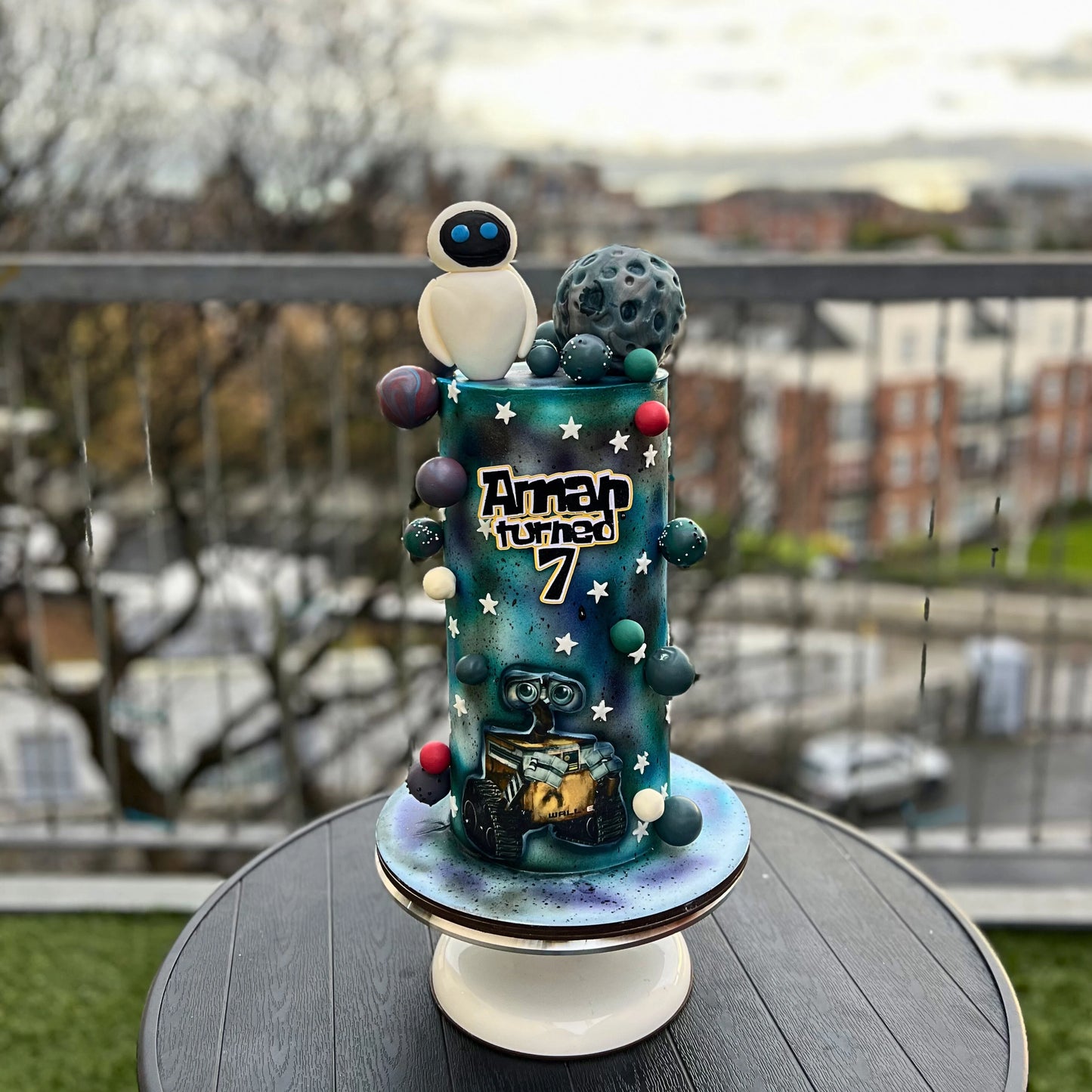 Decorative Custom space themed cake with space character and planet design on a stand outdoors