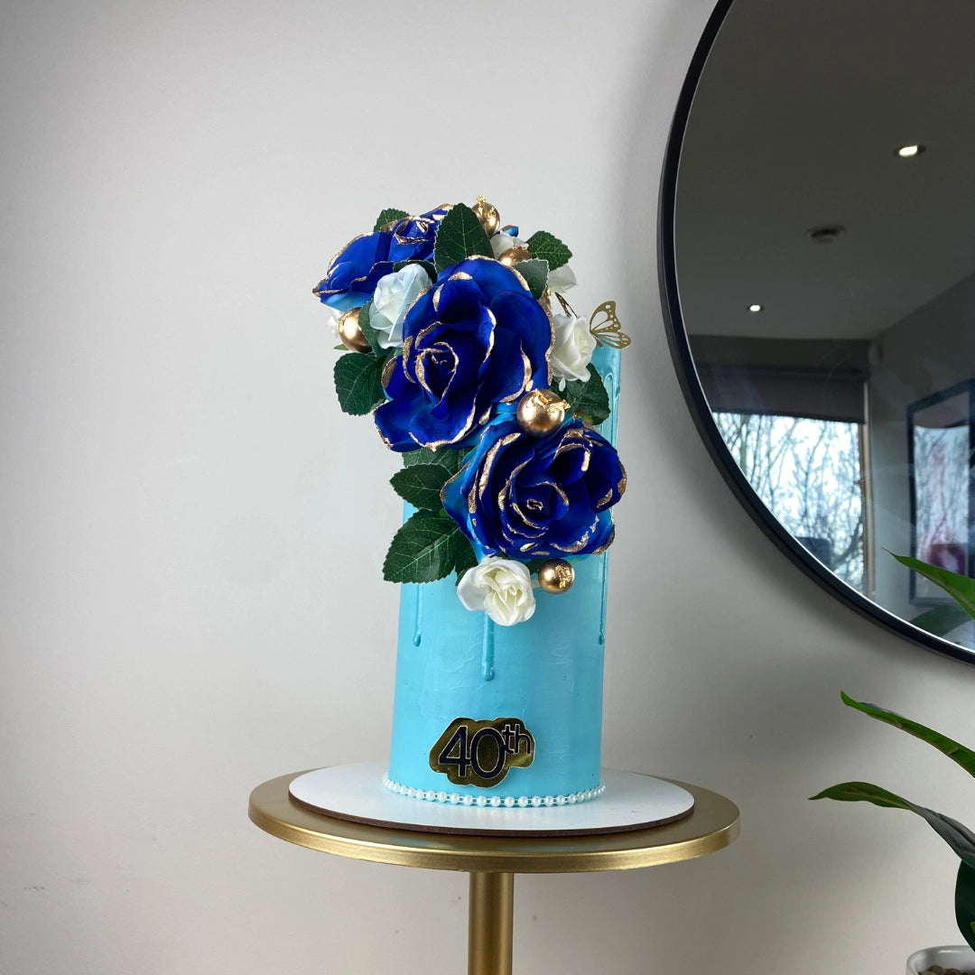 Luxury blue birthday cake with Belgian chocolate and vanilla layers on a cake stand.