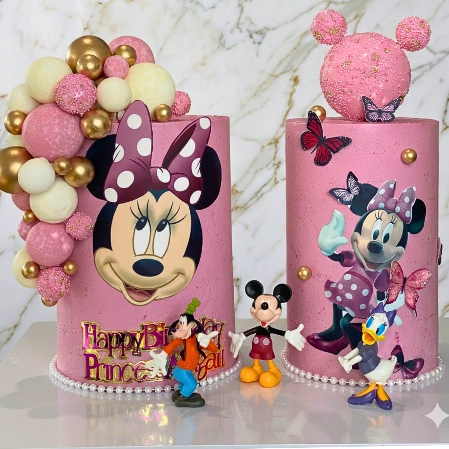 Two pink cylindrical cakes with character designs on a decorated board, Dublin