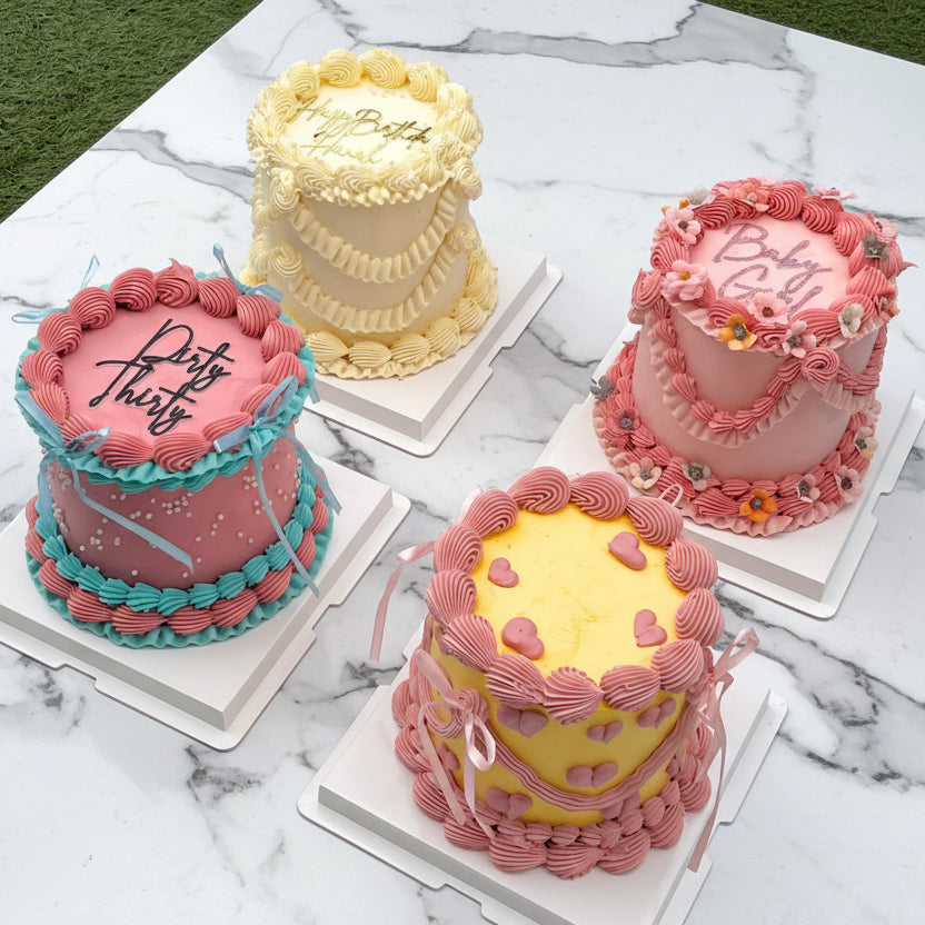 Four colorful cakes on a white table with a grassy background