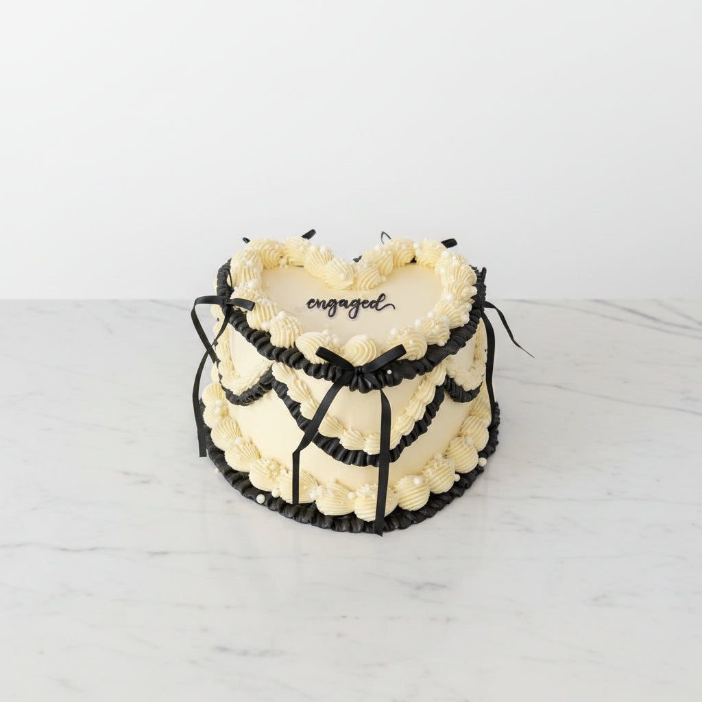 Heart-shaped cake with 'engaged' text on a rooftop with cityscape background