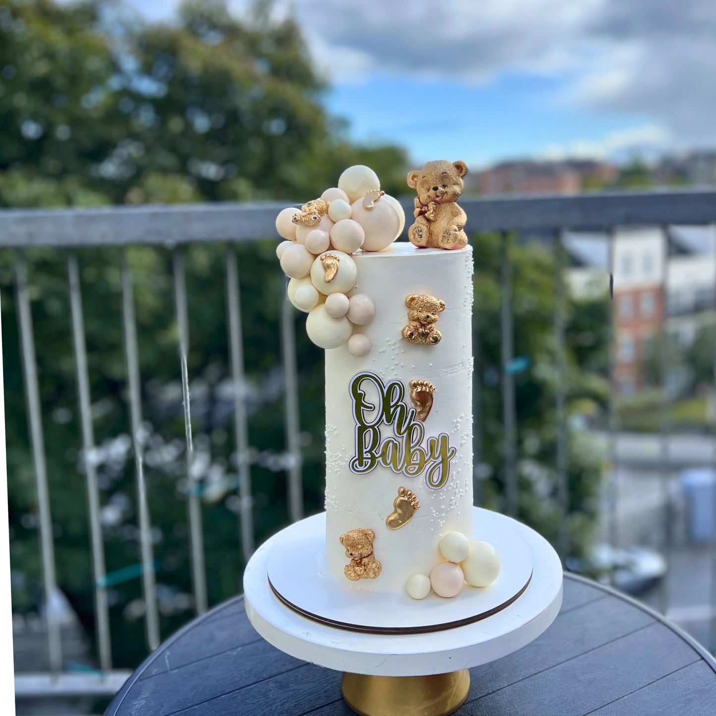 Baby shower cake with teddy bears and balloons on a balcony