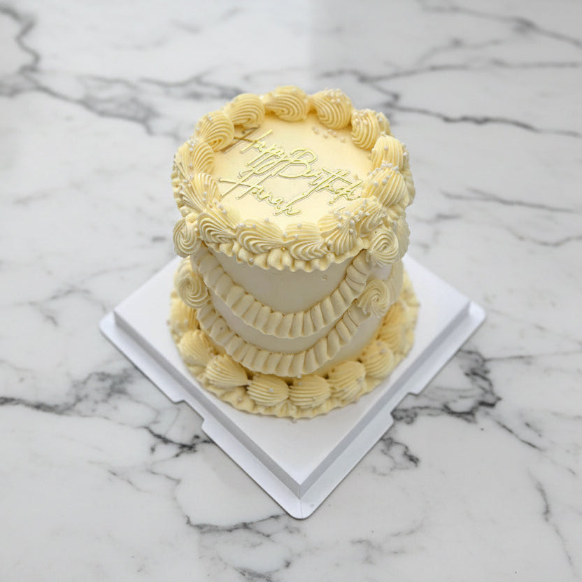 Small white cake with decorative patterns on a white surface